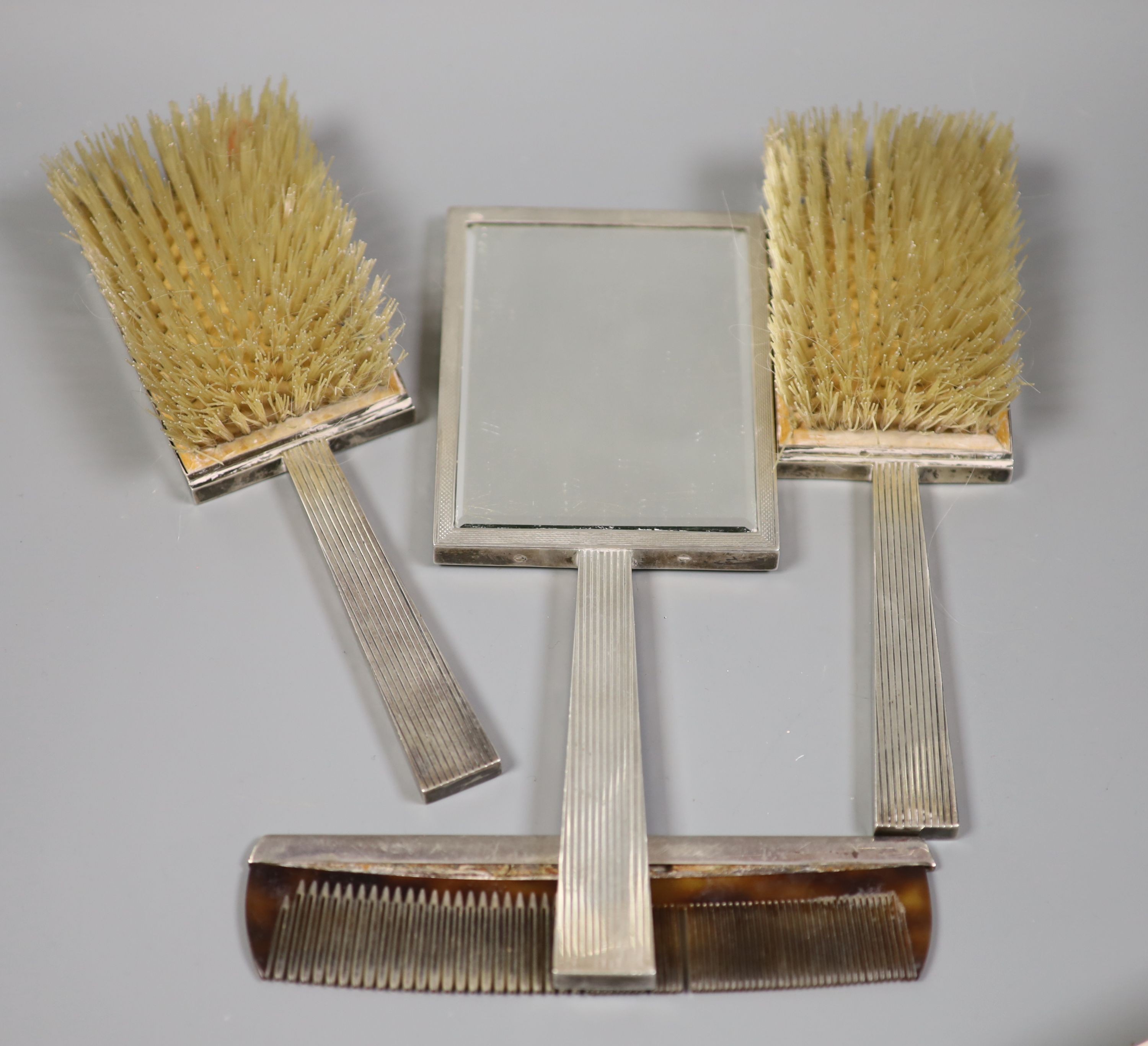 A George VI engine turned silver mounted Art Deco five piece mirror and brush set, S.J. Rose & Son, London, 1947 and an associated silver mounted comb.